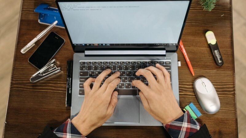 Person typing on a laptop at a cafe table with coffee