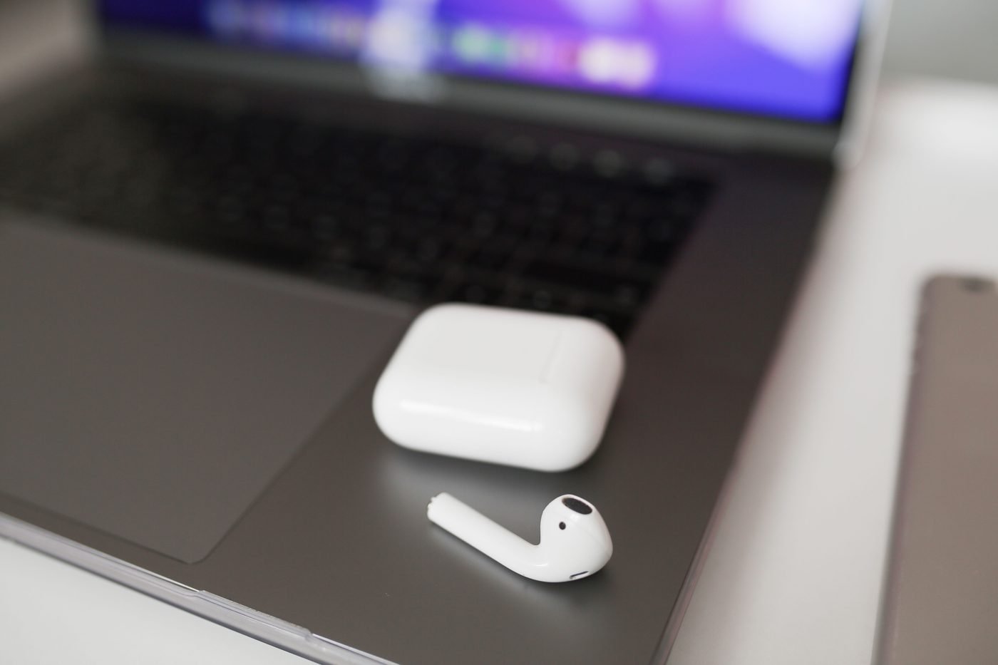 Wireless earbuds and charging case resting on a laptop keyboard