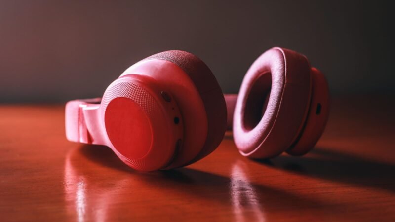Pair of red over-ear headphones resting on a glossy wooden surface