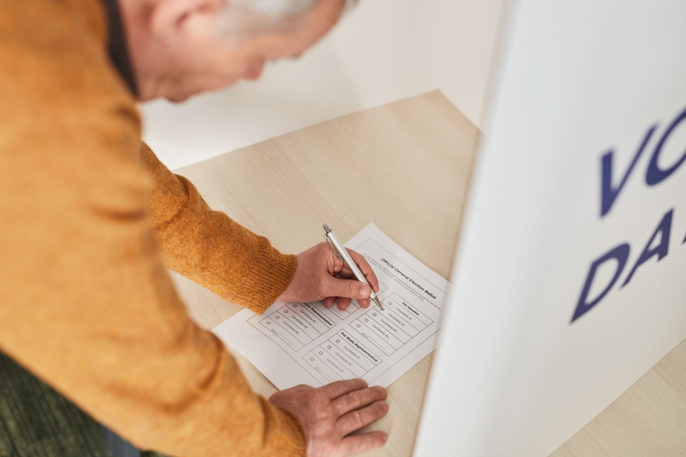 Senior man marking a paper ballot at a voting booth