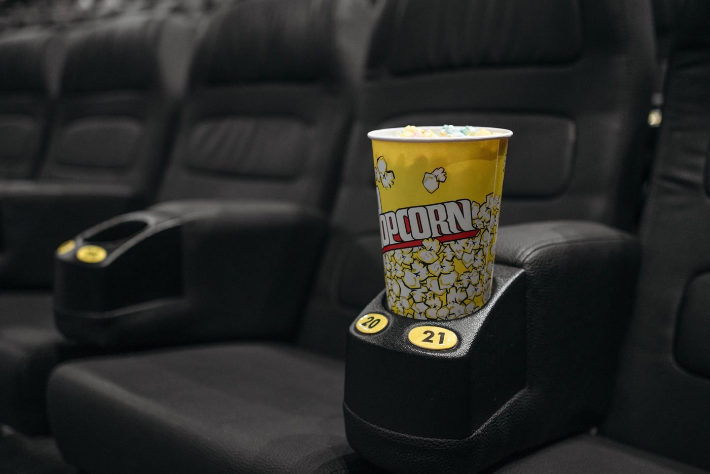 Popcorn bucket in a cup holder between cinema recliner seats