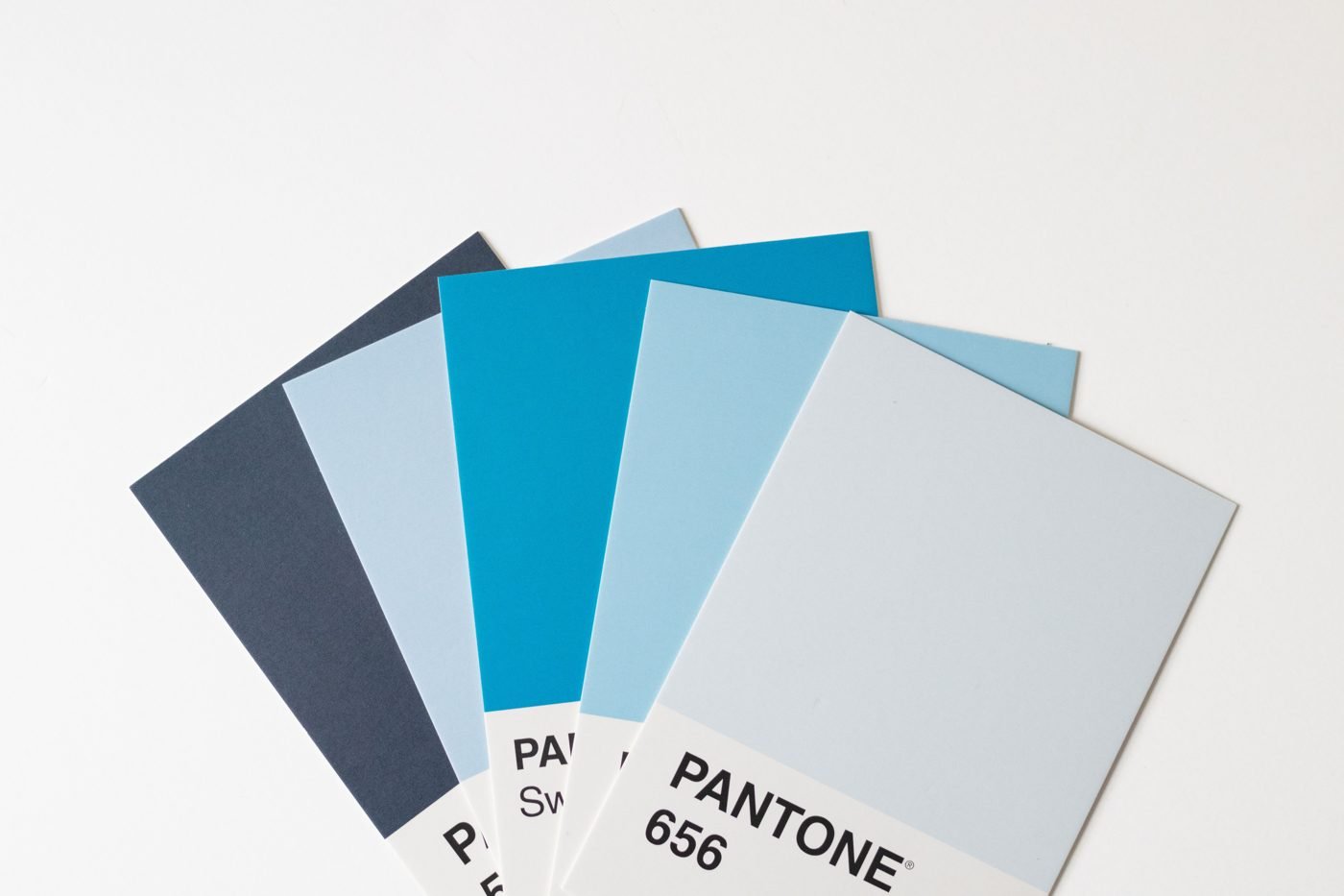 Blue Pantone color swatch cards fanned out on a white background