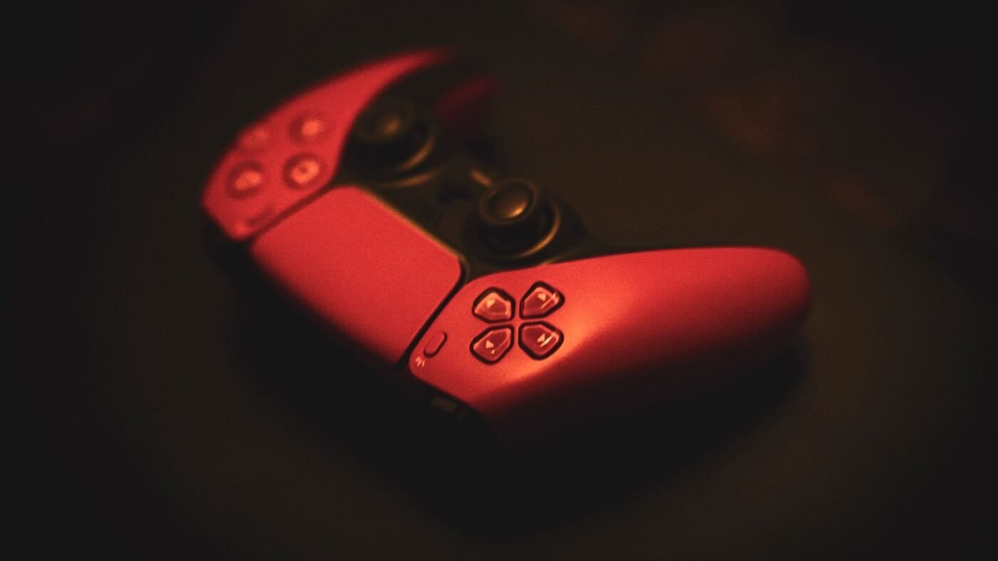 Red game controller lying in moody low light on a dark surface