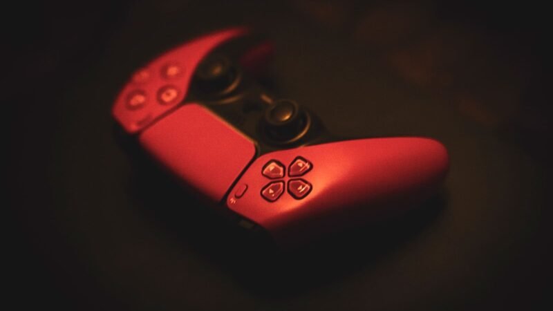 Red game controller lying in moody low light on a dark surface