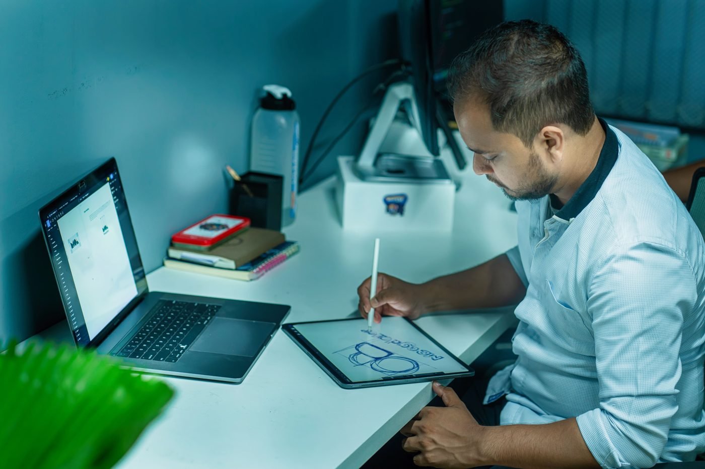 Designer sketching on a tablet next to a laptop at a desk