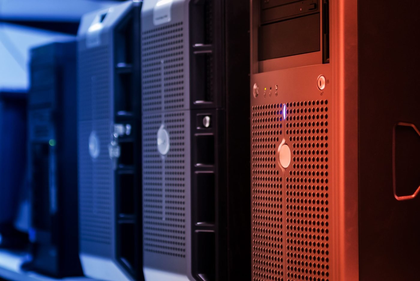 Rows of tower servers in a data center lit in blue and red
