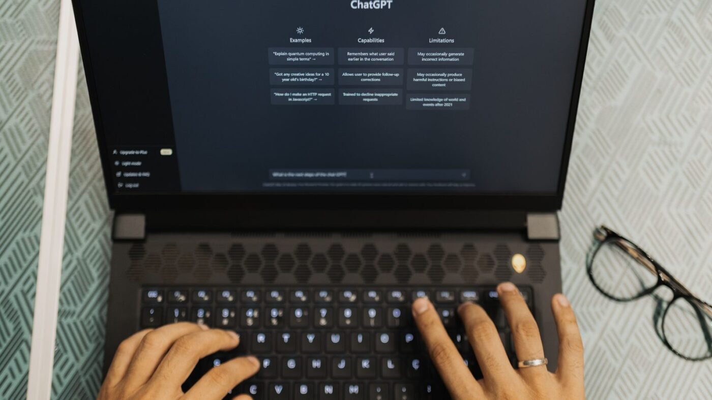 Hands typing on a laptop showing a ChatGPT chat window