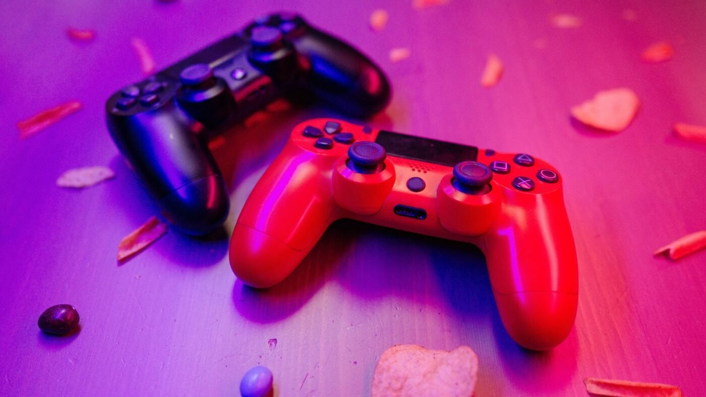 Red and black game controllers on a table under colored light
