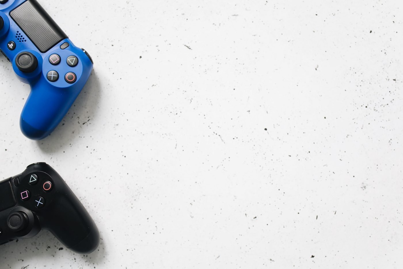 Blue and black PlayStation controllers on a white surface