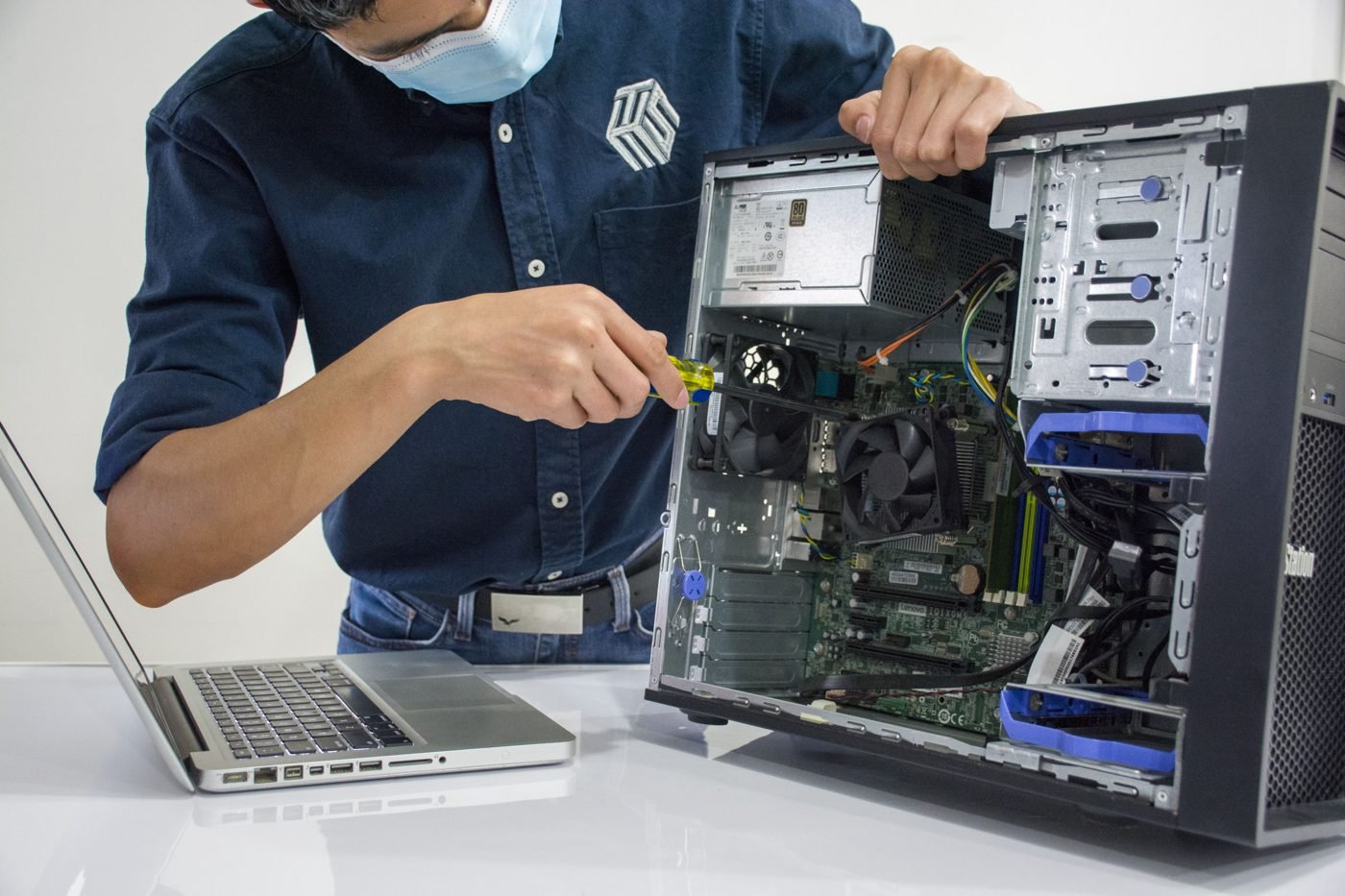 Technician repairing an open desktop computer tower