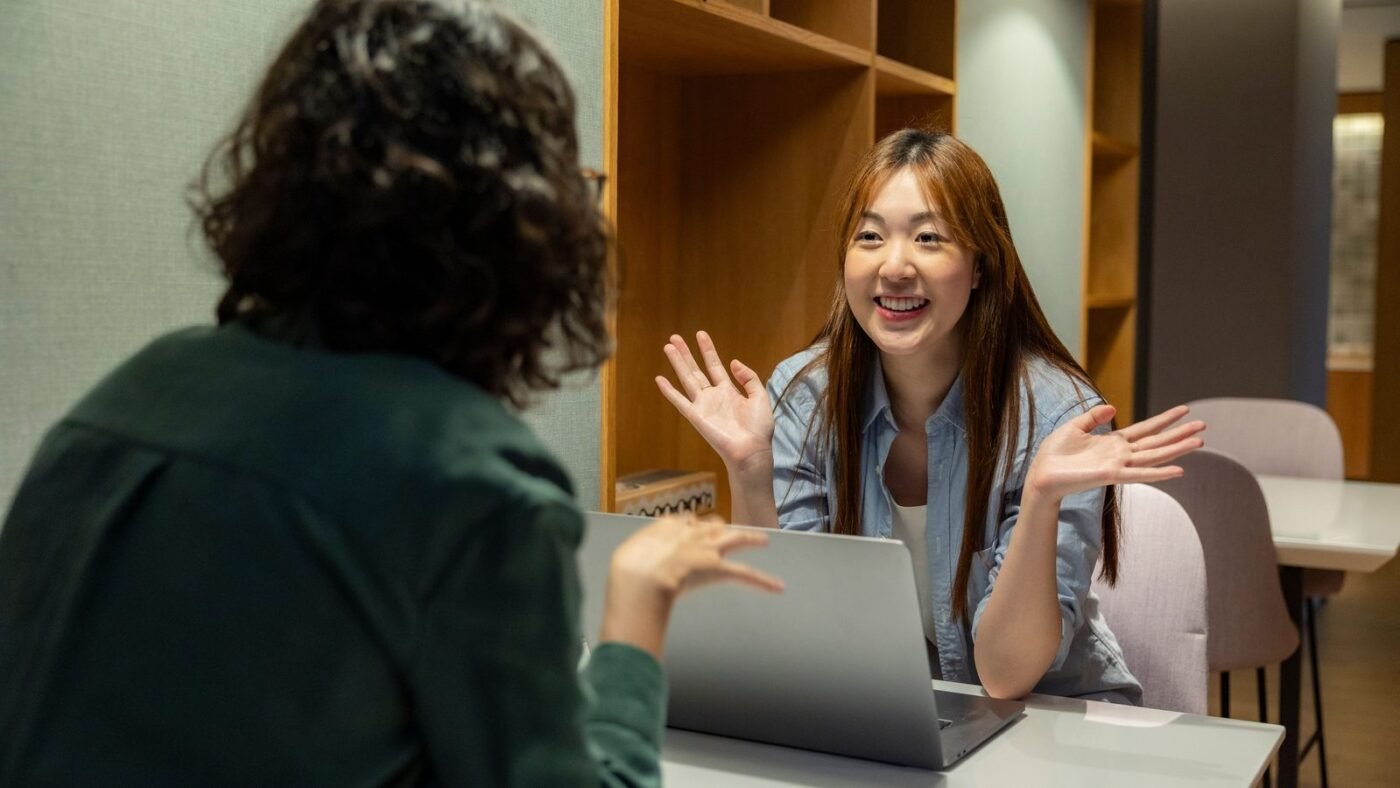 Two colleagues having a friendly one-on-one conversation at an office table