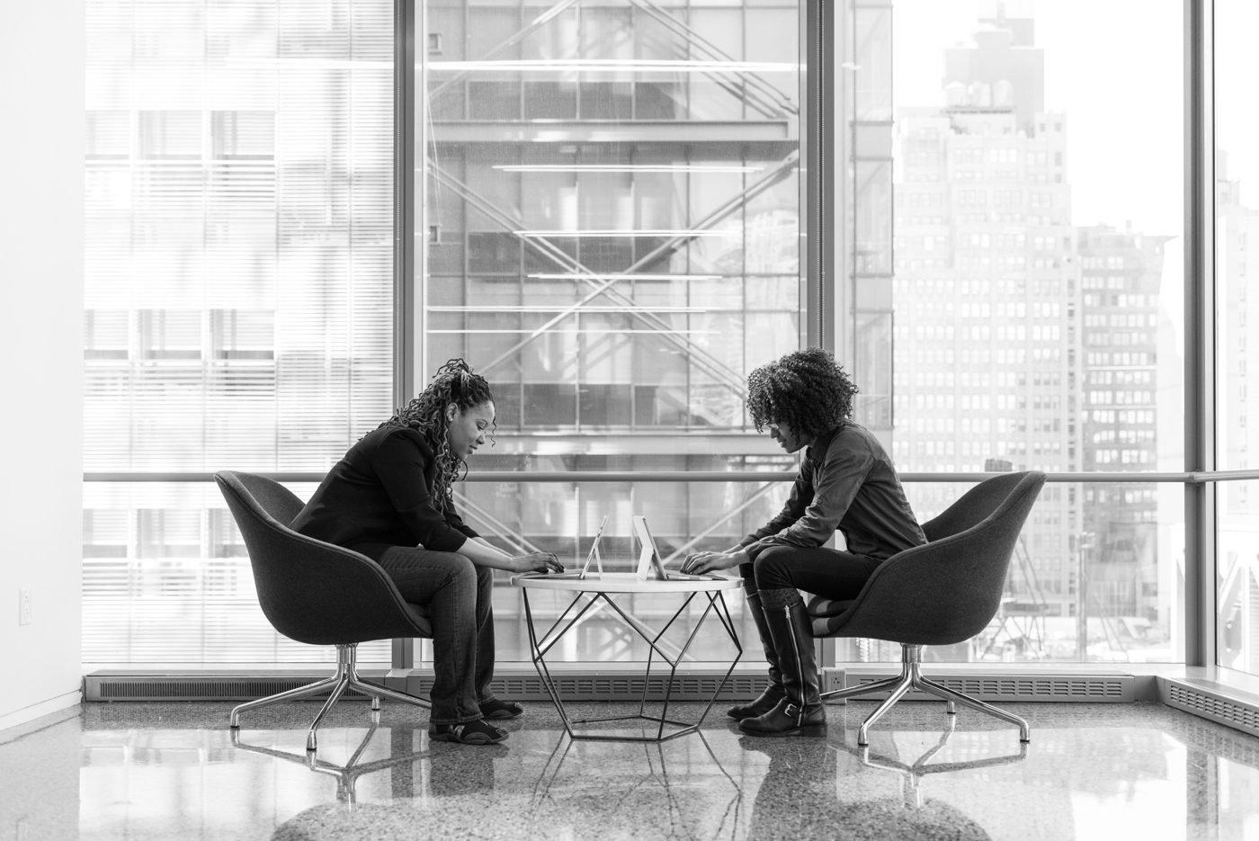 Two professionals in a focused discussion by a large office window