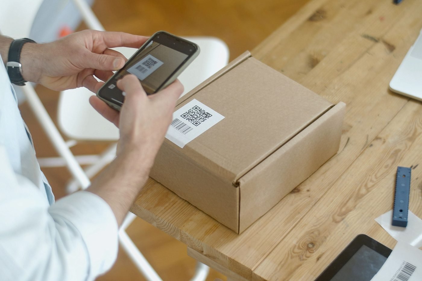 Person scanning a QR code on a cardboard package with a smartphone
