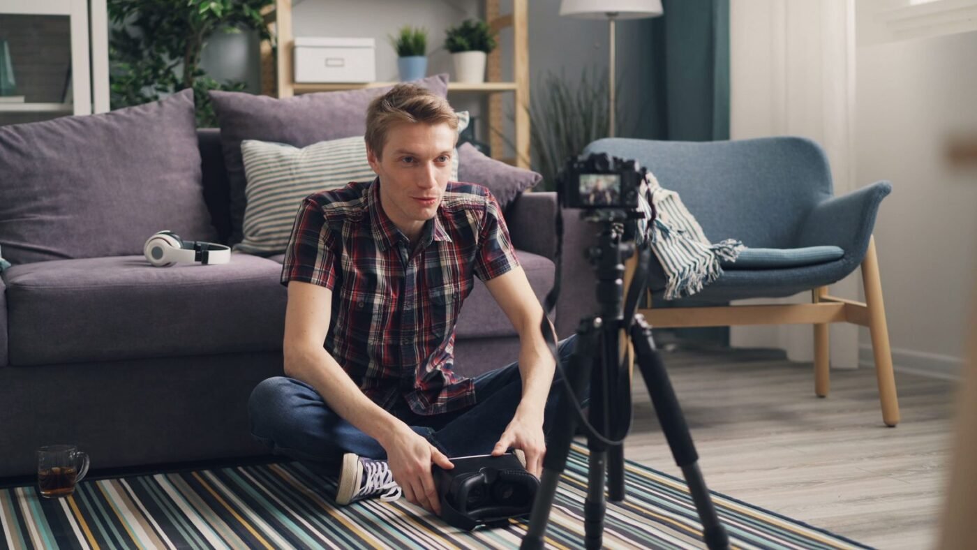 Young man sitting on the floor filming himself with a camera on a tripod