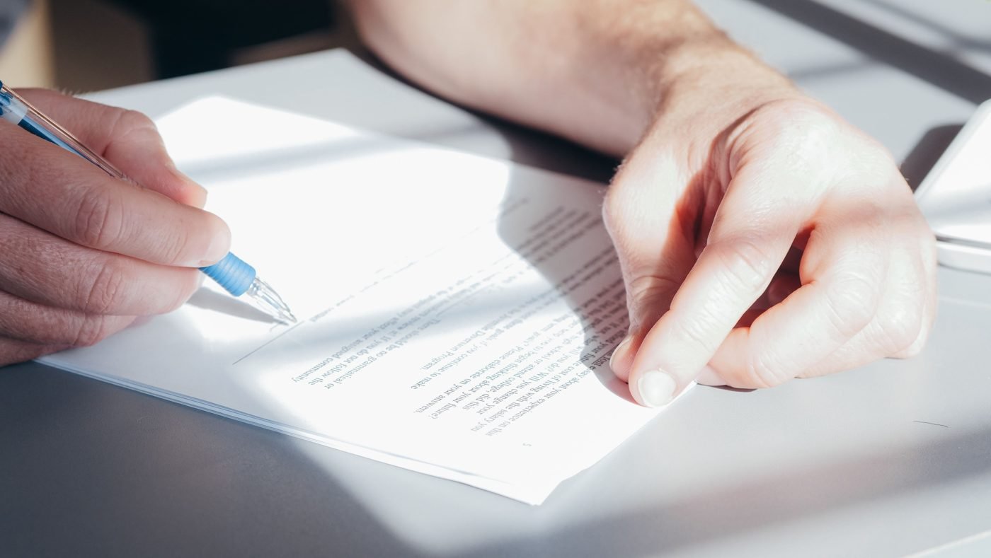 Close-up of a hand signing a document with a pen