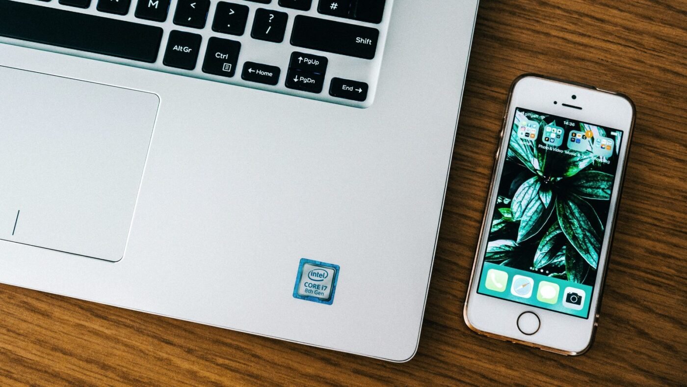 Laptop and smartphone side by side on a wooden desk