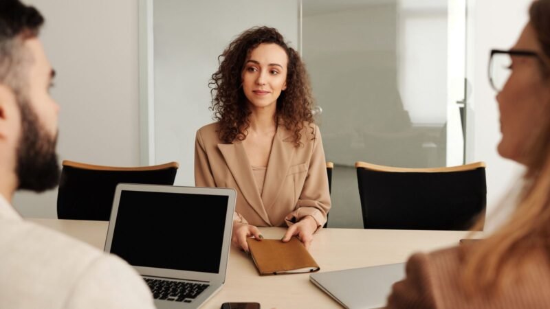 Woman in a business suit during a job interview with two interviewers and a laptop