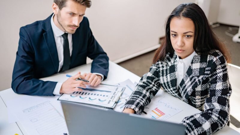 Two colleagues reviewing documents together at an office desk