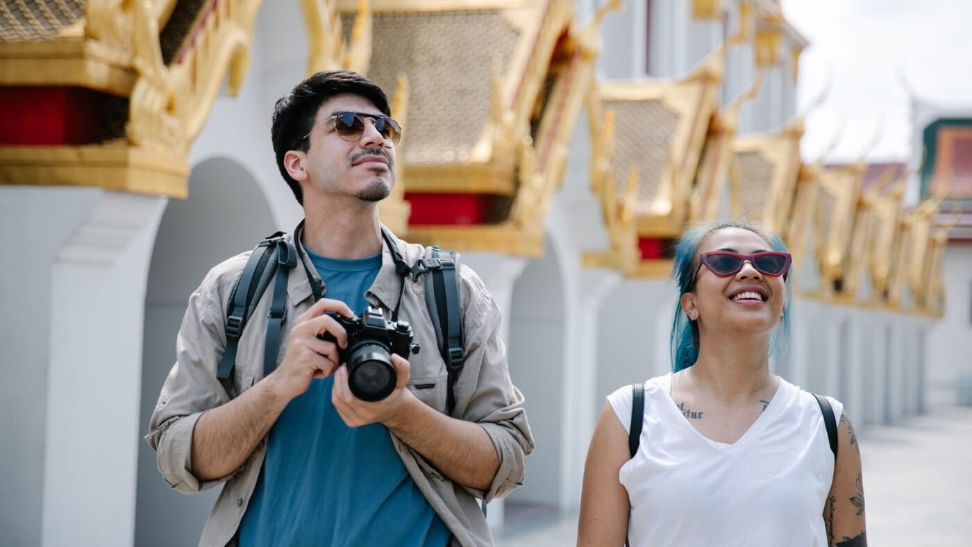 Couple wearing sunglasses exploring ornate city architecture with a camera