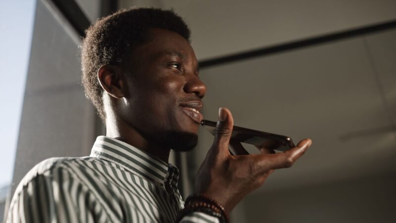 Young man speaking into his smartphone to use a voice assistant
