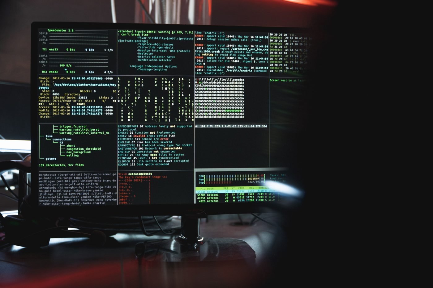 Close-up of a dark computer monitor filled with lines of code and terminal windows