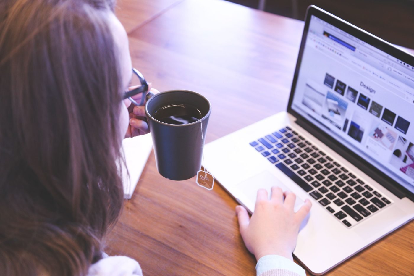 Person holding a mug while browsing a website on a laptop