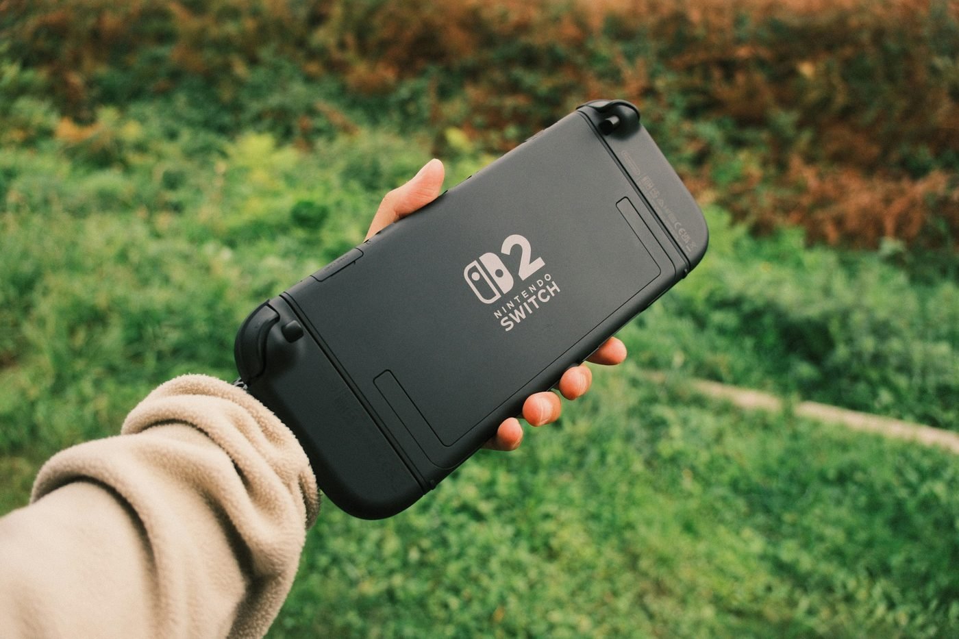 Hand holding a Nintendo Switch 2 console outdoors