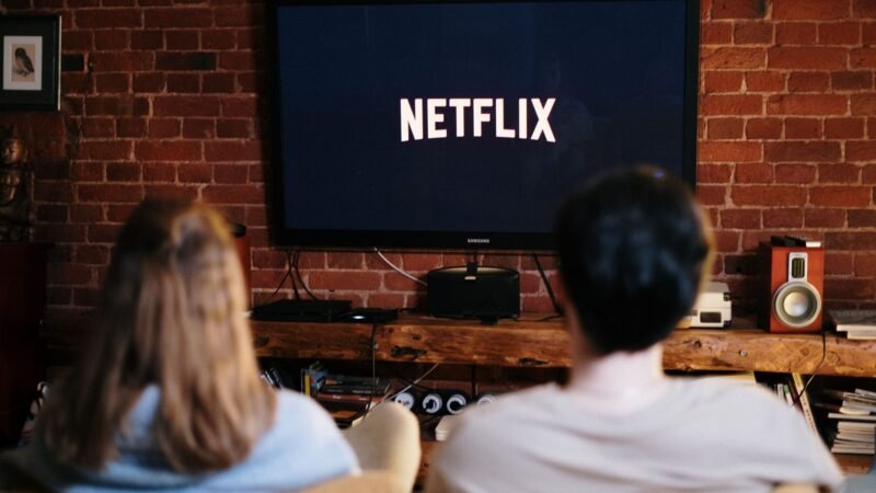 Couple relaxing on a sofa watching Netflix on a wall-mounted TV