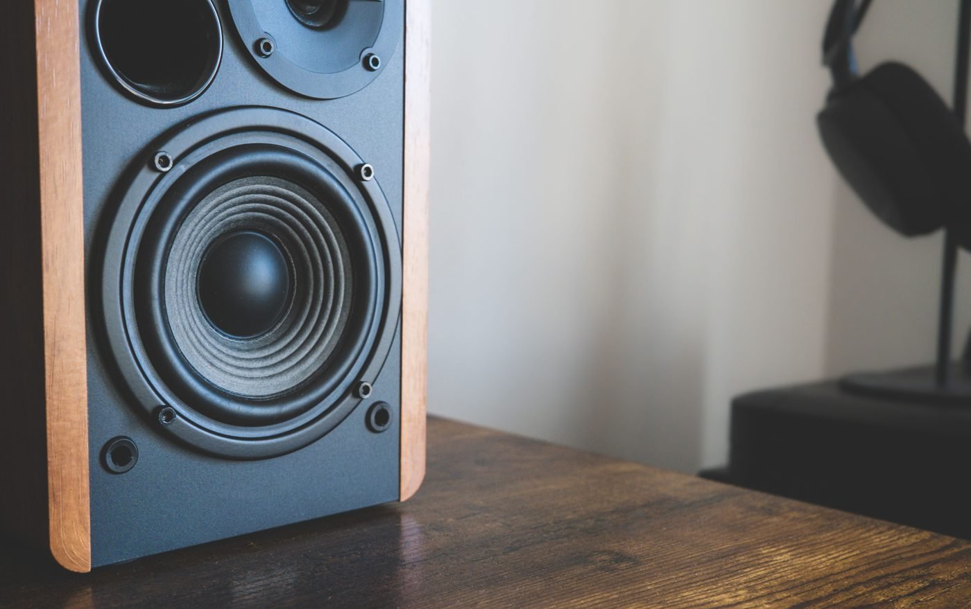 Close-up of a desktop speaker and headphones on a wooden desk