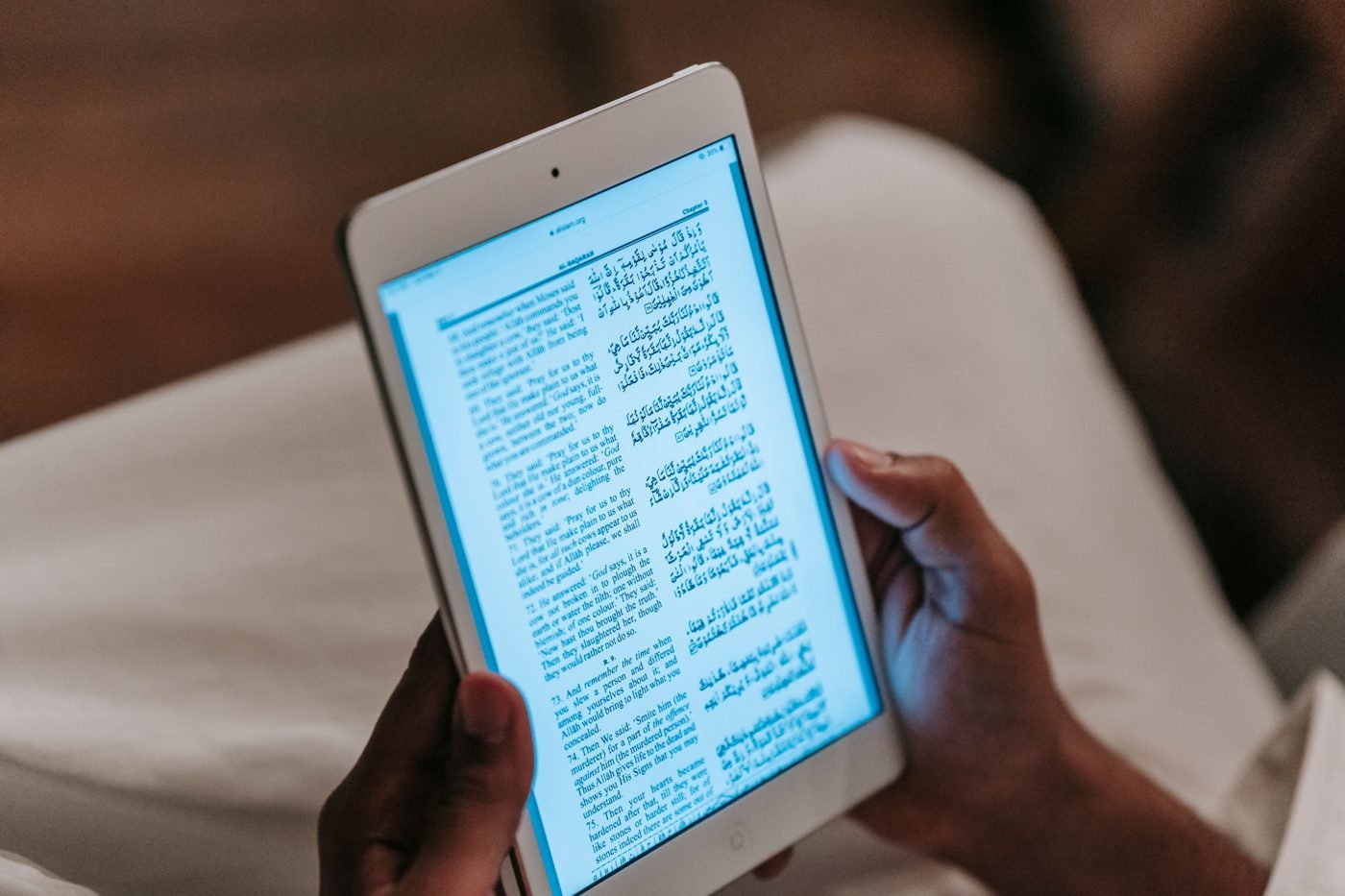 Hands holding a small tablet while reading an article