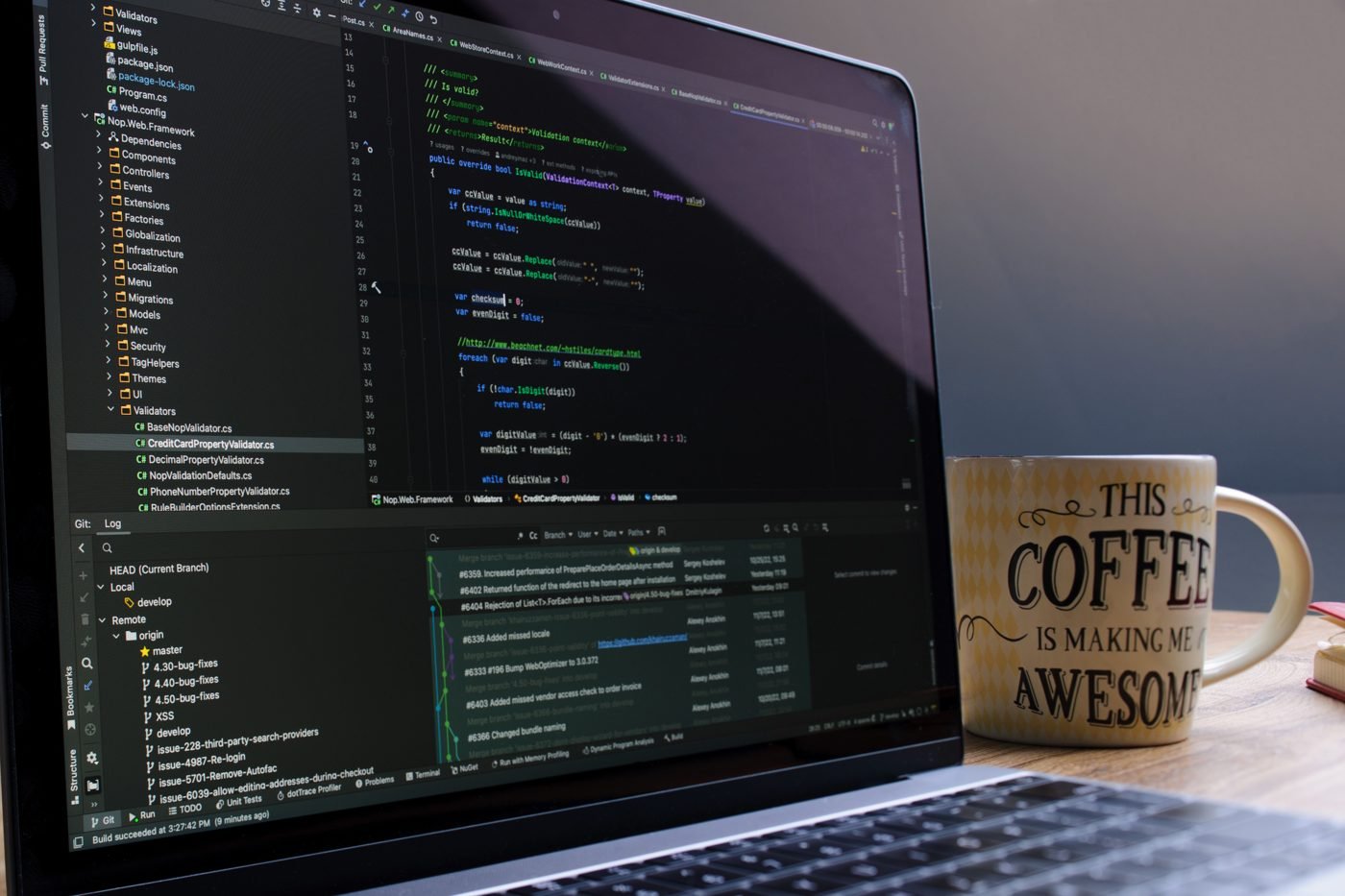 Laptop on a desk showing lines of code next to a coffee mug