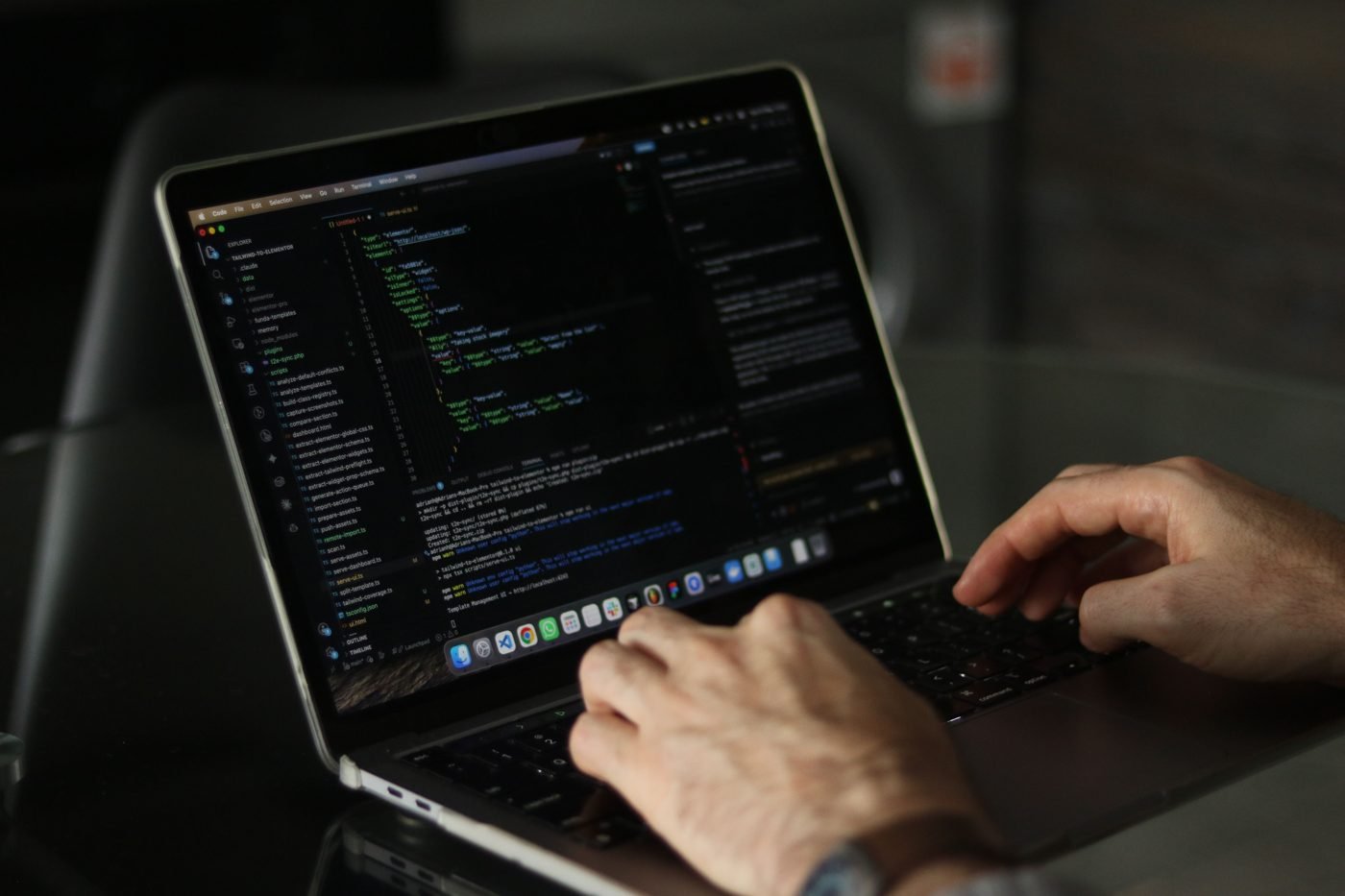 Developer typing code on a laptop in a dark room