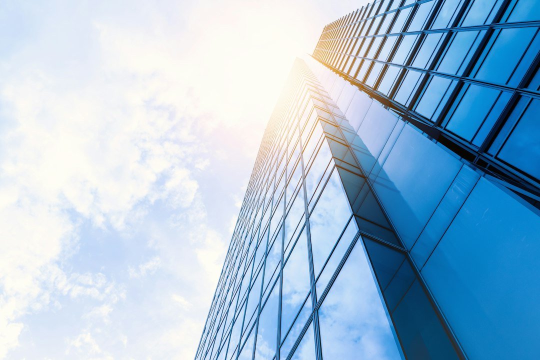Glass-walled corporate office tower against a blue sky