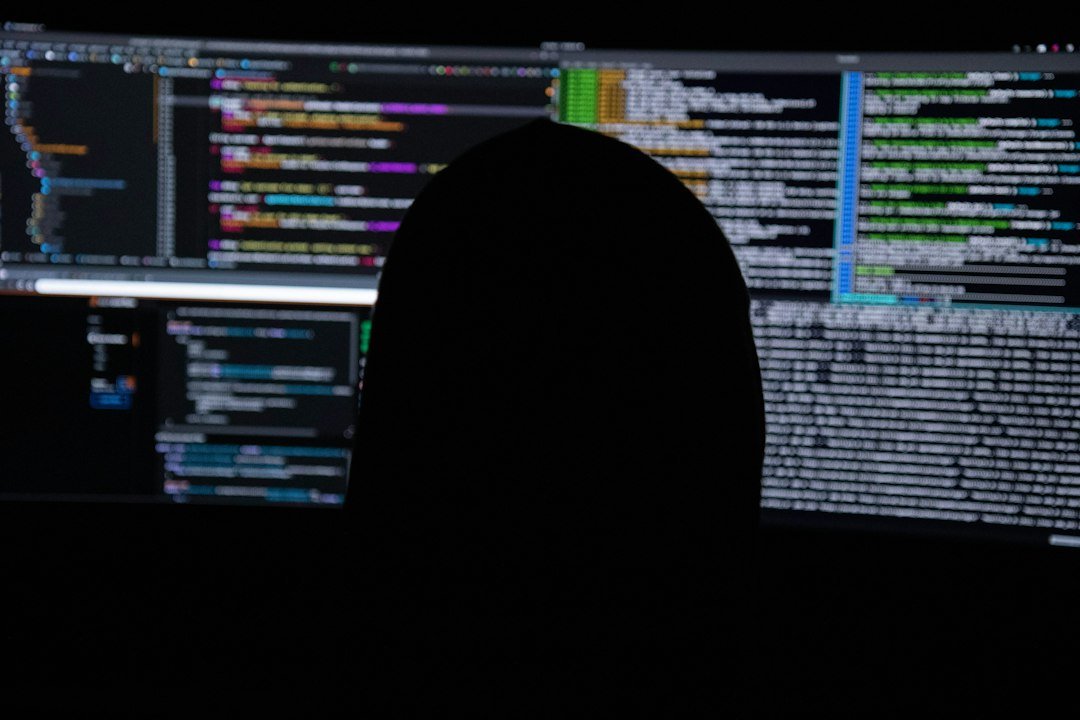 Silhouette of a person against multiple monitors showing code