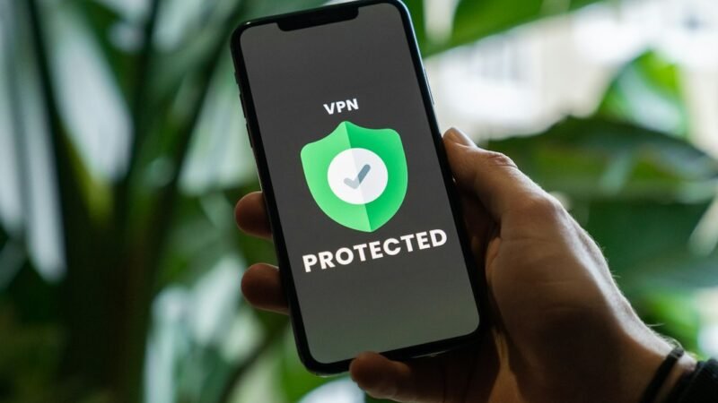 Hand holding an iPhone with a VPN privacy service enabled on screen