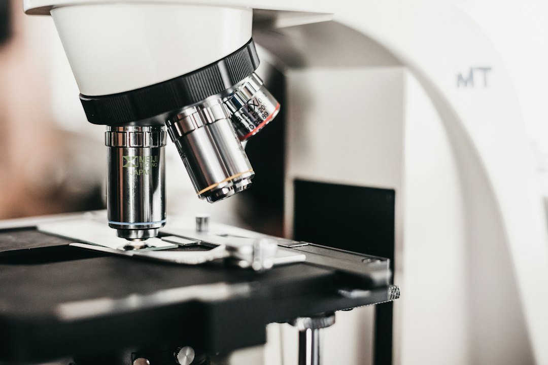 A lab microscope with multiple objective lenses above a black stage