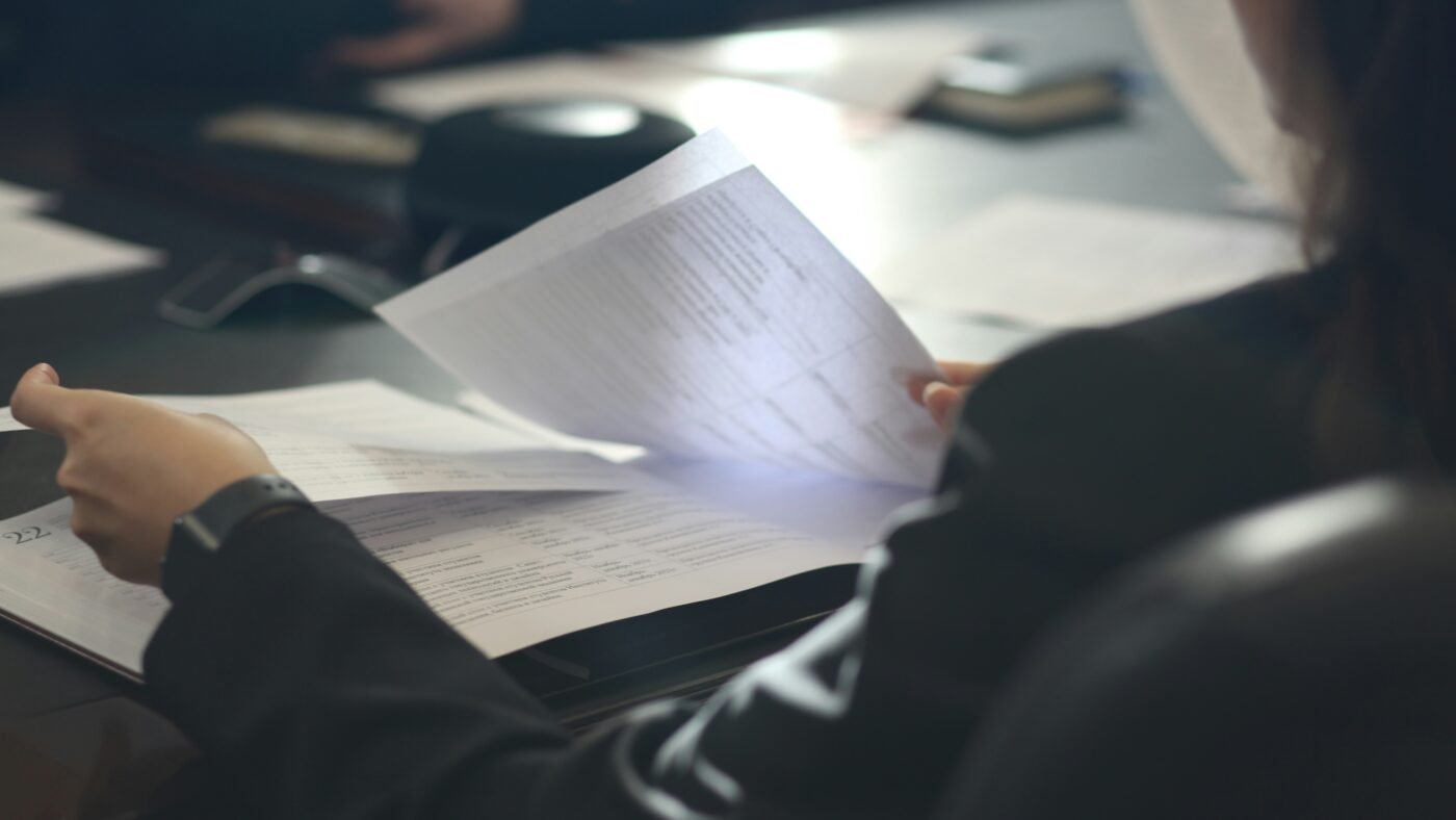 Person reading a printed letter at a desk, representing fired OpenAI researchers publishing an open letter