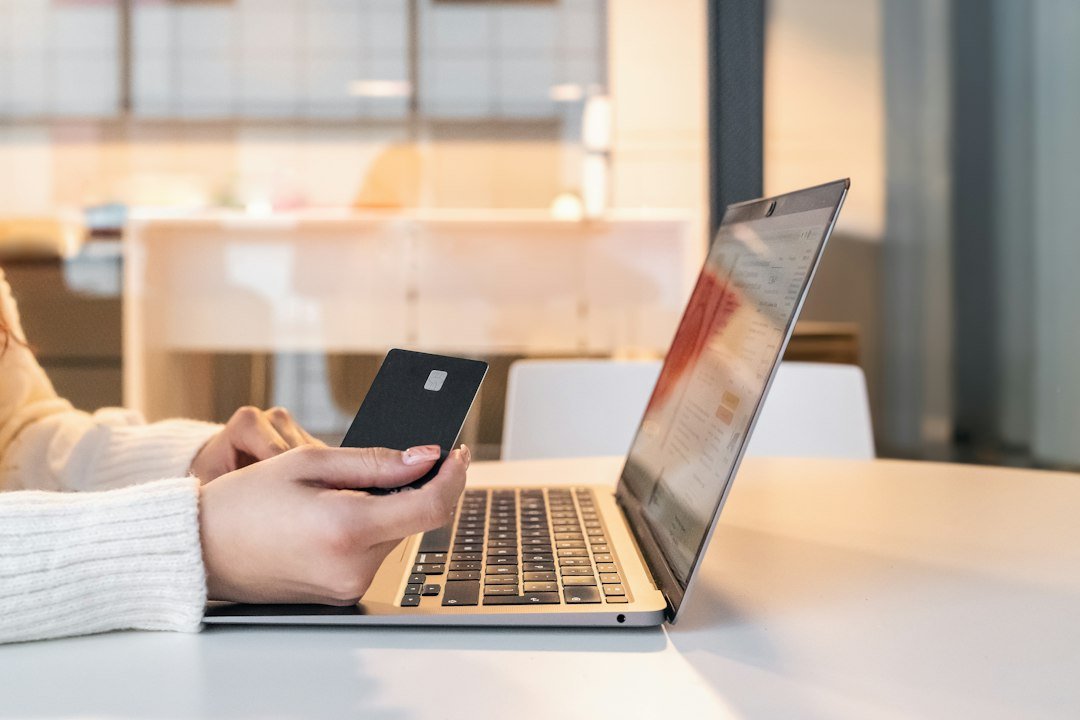 Woman holding a credit card near a laptop while shopping online