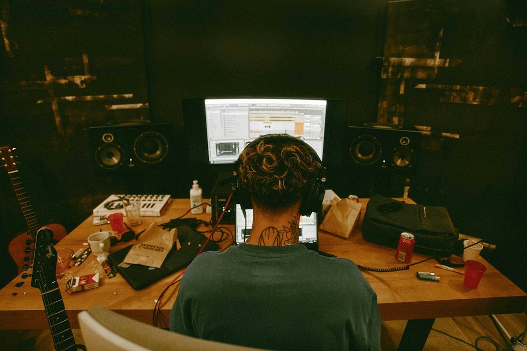 Man sitting at a desk with a guitar in a home recording setup
