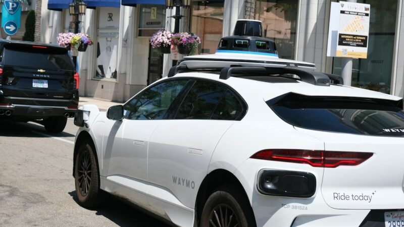 White Waymo autonomous vehicle with roof sensors parked on a city street