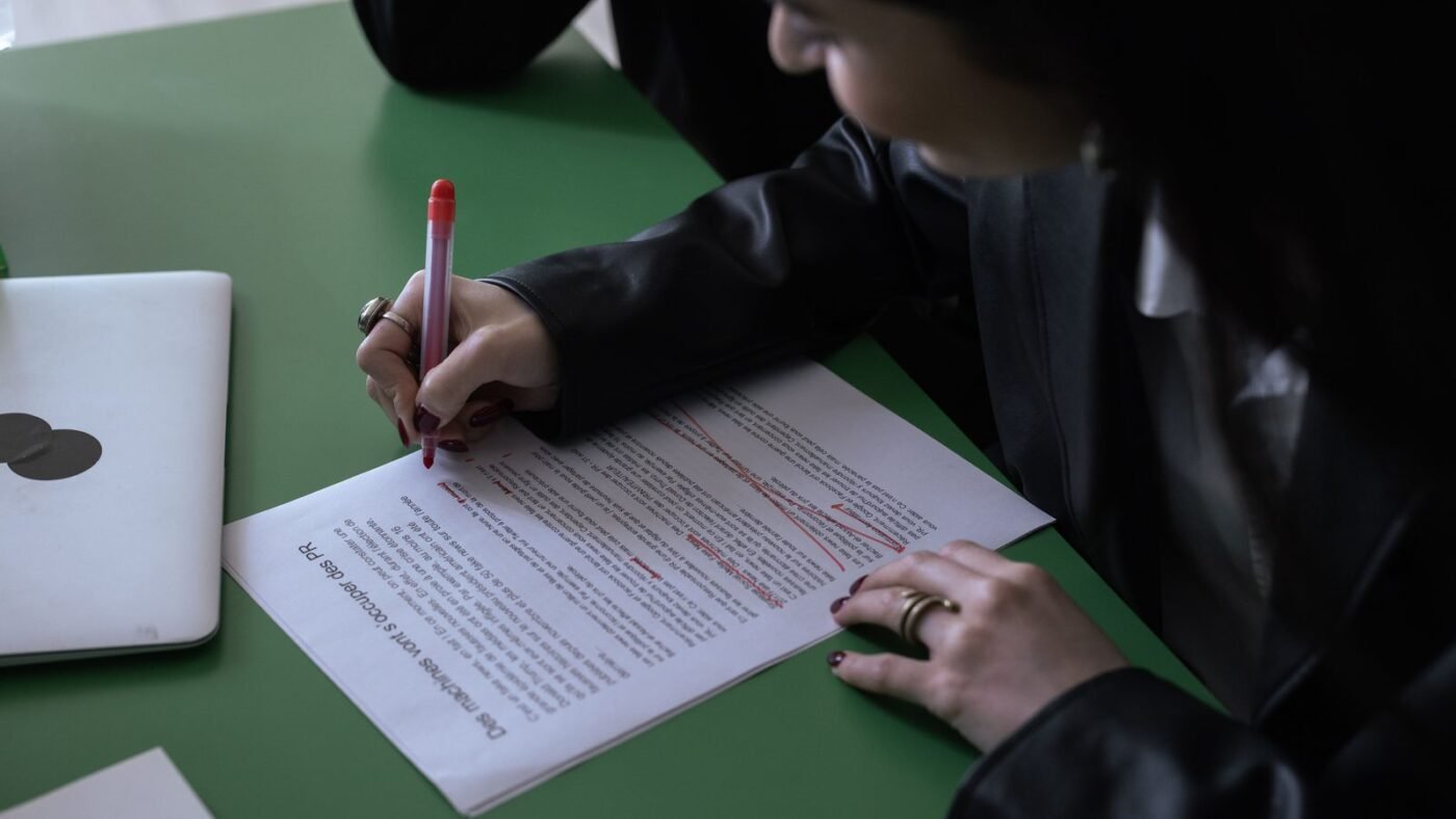 Woman marking up a printed document with a red pen at a desk