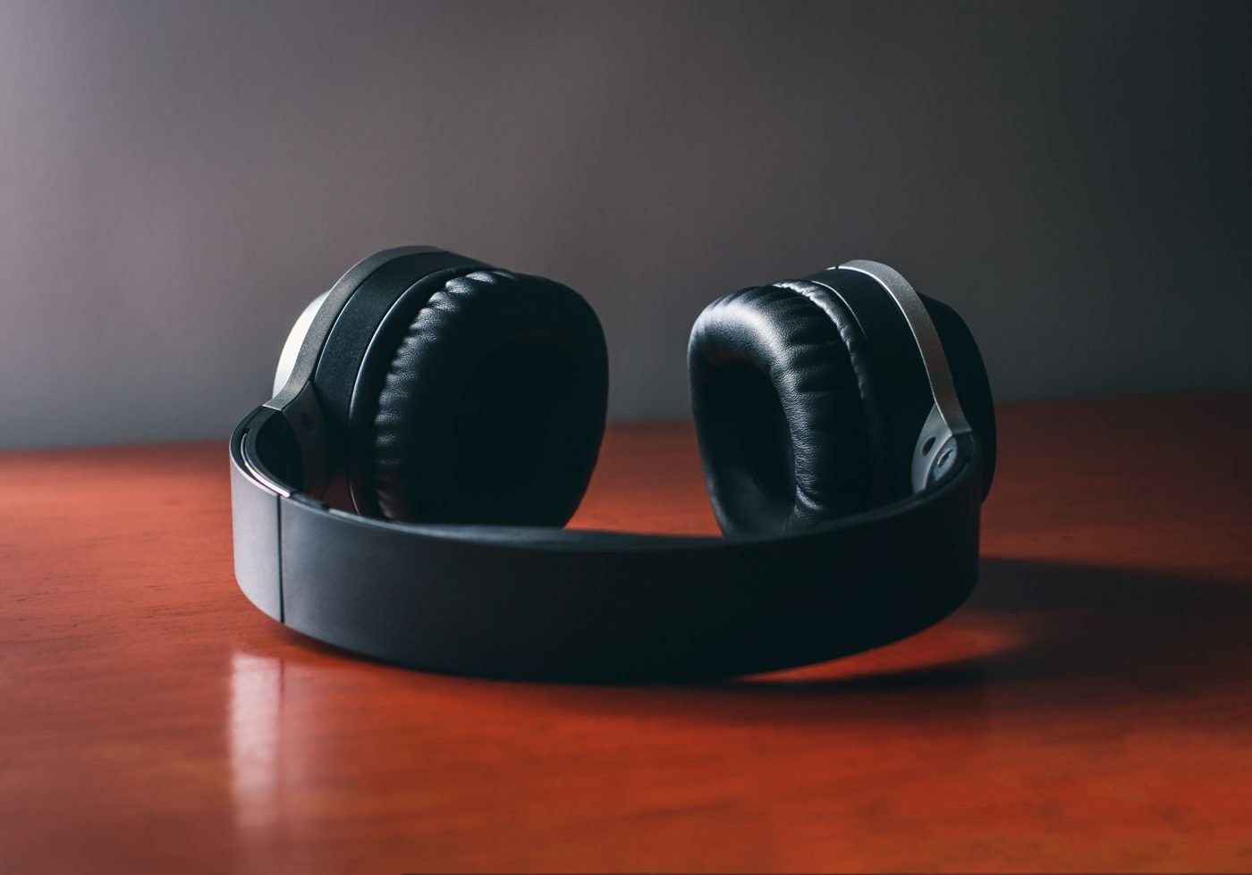 Black wireless headphones resting on a polished wooden table