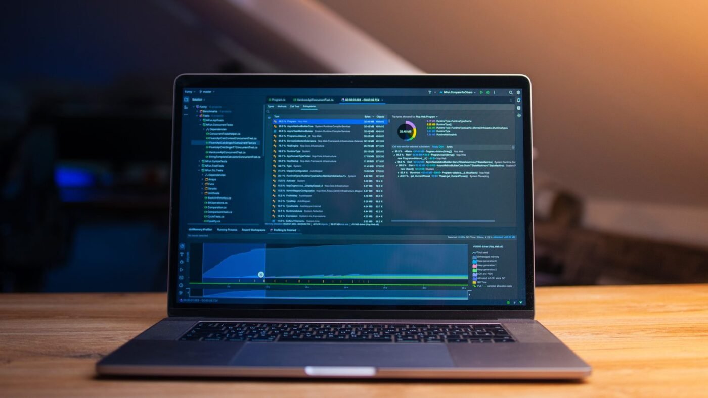 Laptop displaying lines of code on a wooden desk in a dimly lit room