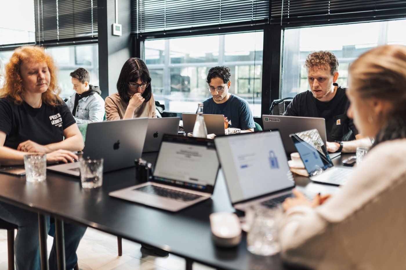 Team of colleagues working on laptops around a shared office table