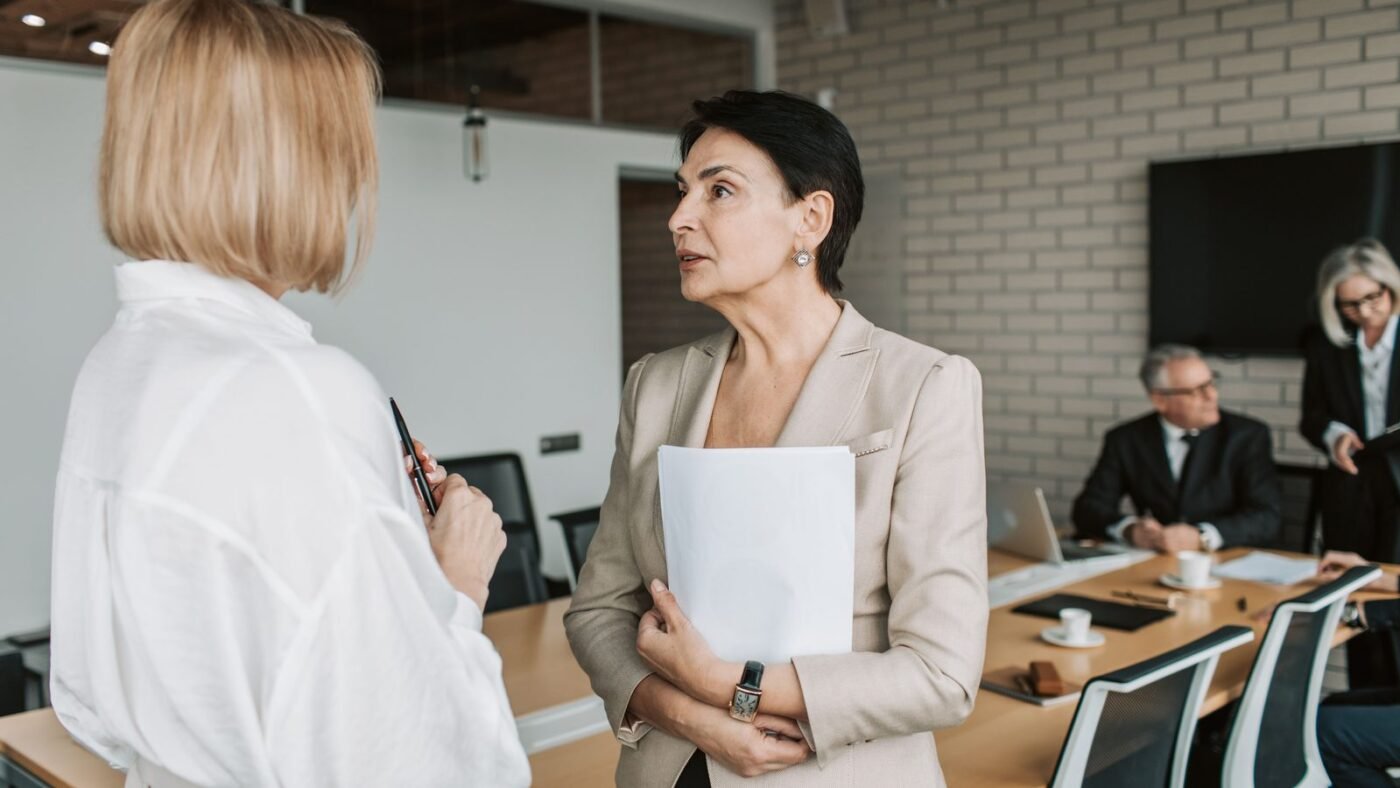 Two professionals talking across a meeting table in an office