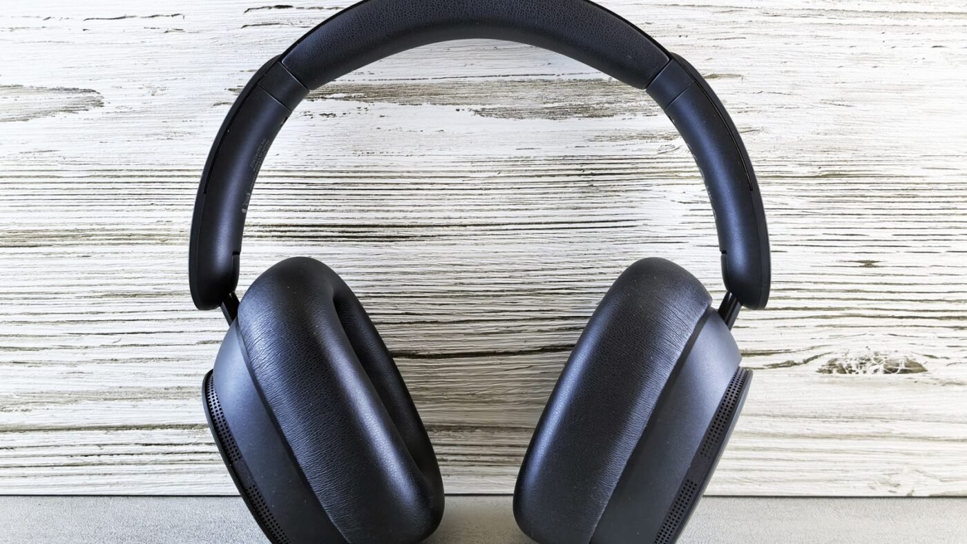Pair of dark over-ear wireless headphones standing on a white wooden surface