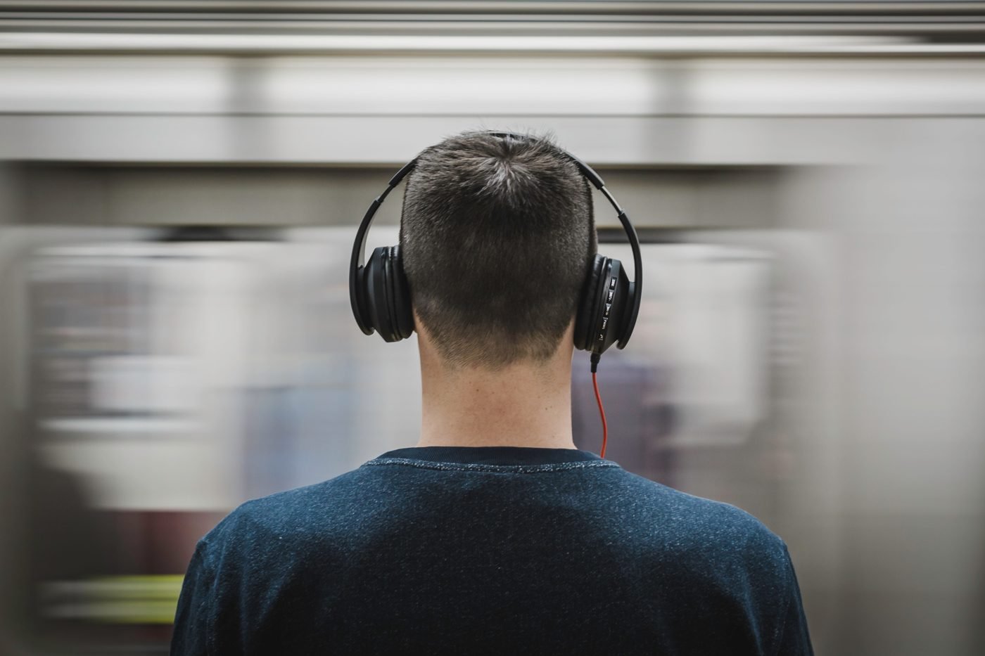 Man wearing over-ear headphones as a train rushes past