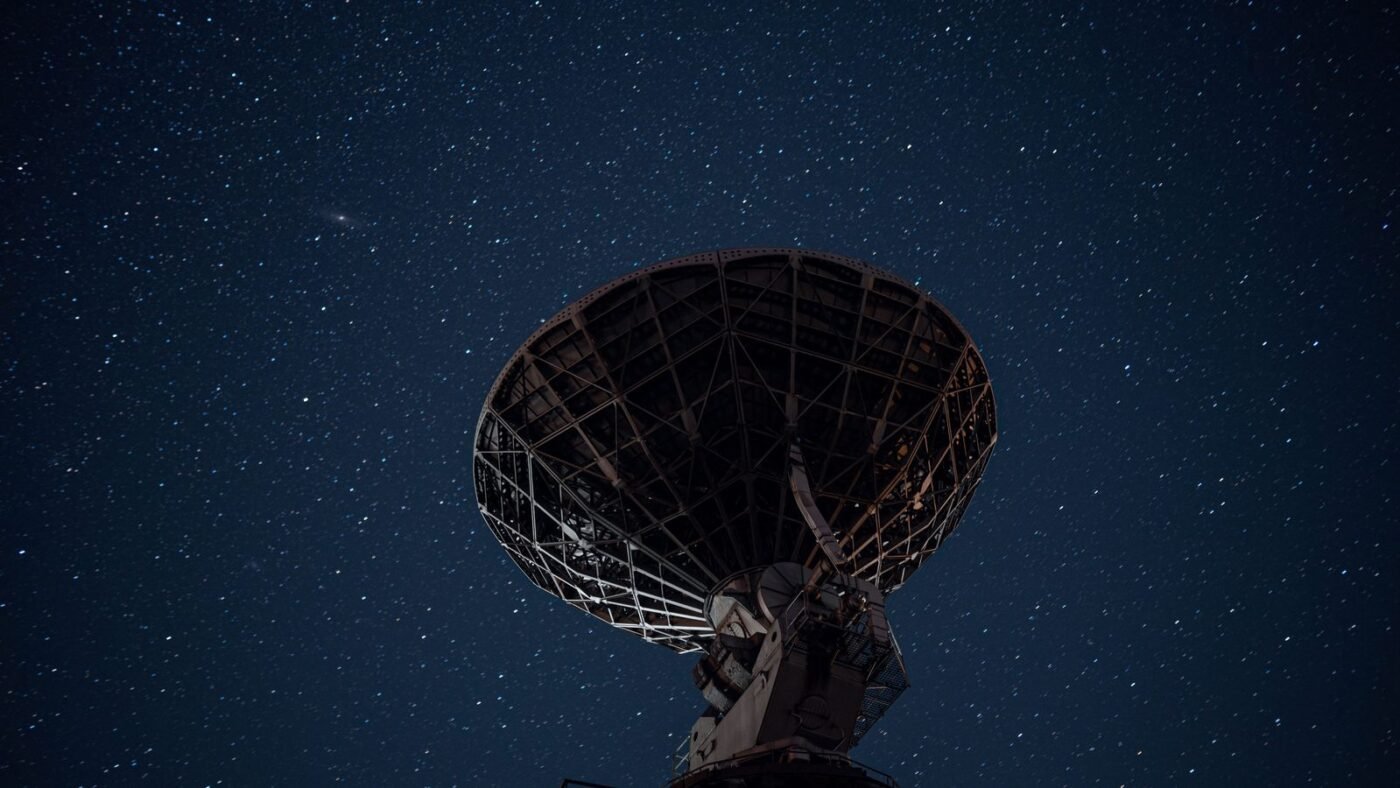 Large satellite dish silhouetted against a starry night sky