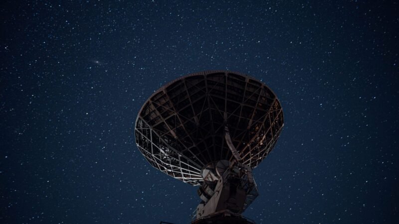 Large satellite dish silhouetted against a starry night sky