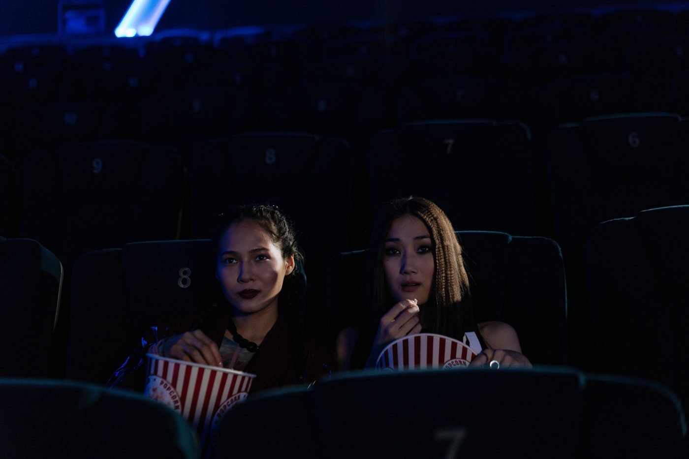 Two moviegoers eating popcorn in a dark cinema